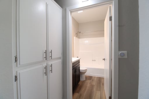 a view through a door into a bathroom with a toilet and sink with hallway abundant cabinet storage