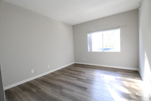 an empty room with wooden floors and a window