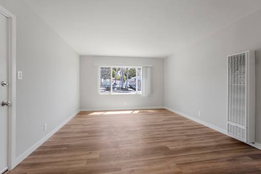 A room with wooden floors and a window showing a view of trees.
