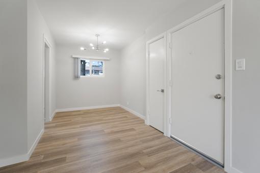 A room with a white door and a window with a view of a building outside.