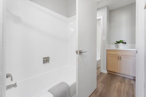 A white bathroom with a wooden cabinet and a plant on top.