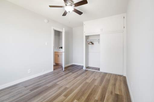 A room with a ceiling fan and wooden flooring.