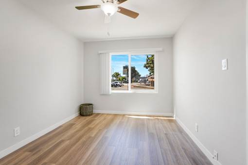 A room with a ceiling fan and a window with a view of the outside.