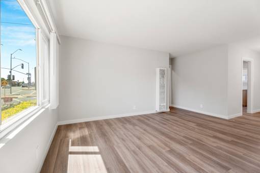 A room with a window and a wooden floor.