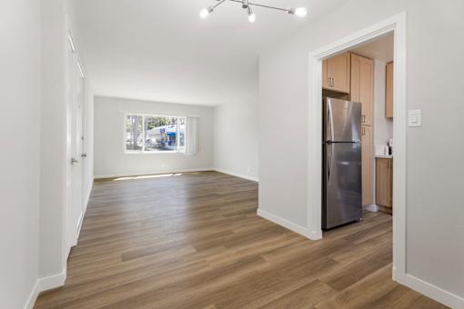 A kitchen with a refrigerator and wooden floors.