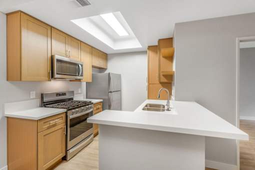A kitchen with a white countertop and wooden cabinets.