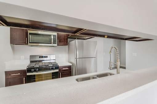 A kitchen with a stove, microwave, refrigerator, and sink.
