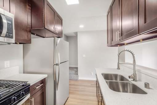 A kitchen with a stove, refrigerator, and sink.