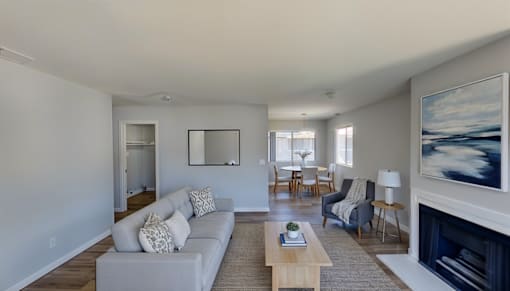 A living room with a grey couch and a fireplace.