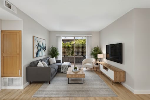 A living room with a grey couch, a coffee table, a chair, and a painting on the wall.