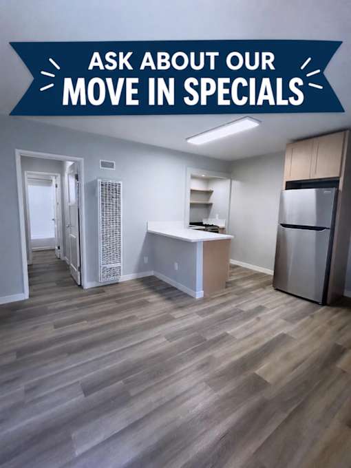 A kitchen area with a refrigerator, sink, and cabinets.
