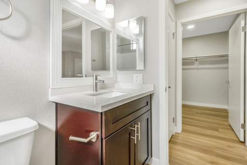 A bathroom with a sink, mirror, and toilet.
