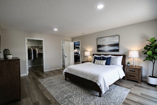 A bedroom with a large bed, a wooden dresser, and a potted plant.