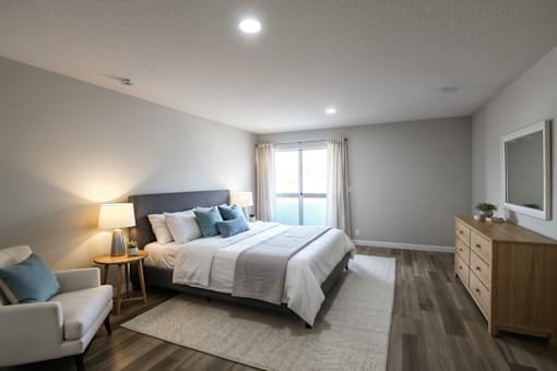 A bedroom with a large bed, a chair, and a nightstand.