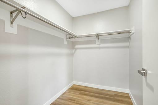 A white wall with a wooden floor and a metal rack on it.