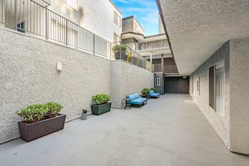 A courtyard with a white wall and a blue chair.