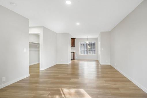 A long, empty hallway with wooden floors and white walls.