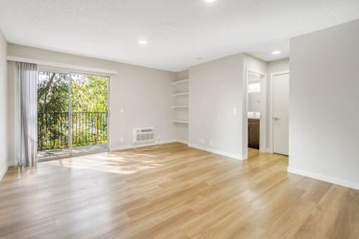 A spacious room with wooden floors and white walls.