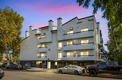 A modern apartment building with cars parked in front.