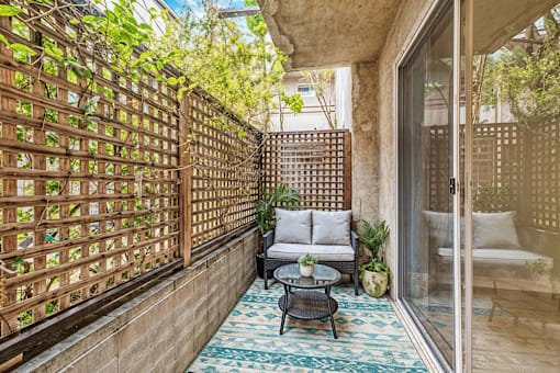 A patio with a table and chairs and a lattice fence.