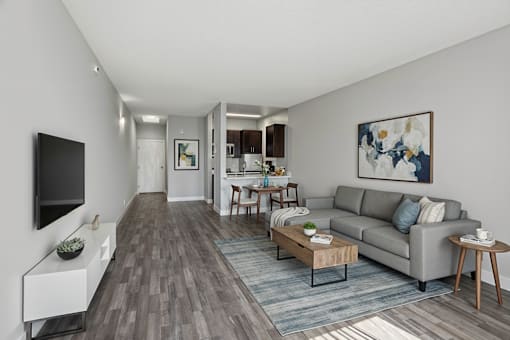 A living room with a grey couch, a coffee table, and a painting on the wall.