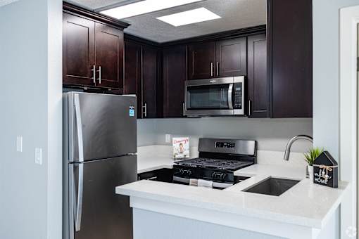 A kitchen with a refrigerator, microwave, and stove.