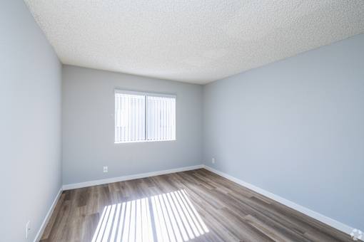 A room with a window and wooden flooring.