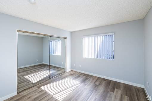 A room with a wooden floor and a large mirror on the wall.