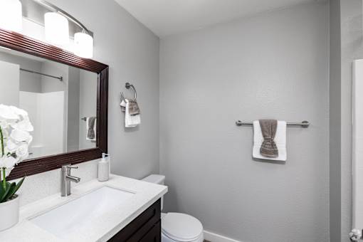 A white sink with a mirror above it and a towel hanging on the wall.
