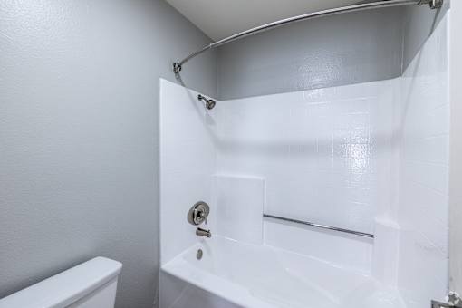 A white bathroom with a toilet, sink, and shower.