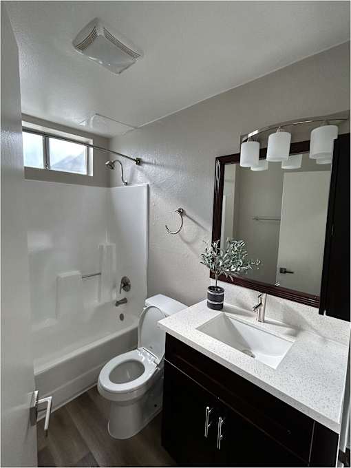 A white toilet in a bathroom with a sink and mirror.
