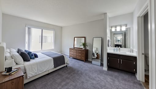 A bedroom with a large bed and a vanity with a mirror.