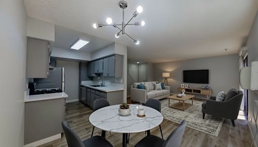 A modern living room with a dining table and grey chairs.