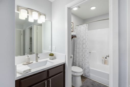A white toilet sits in a bathroom next to a white sink.
