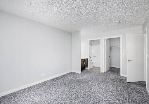 A sparsely furnished room with a carpeted floor and white walls.