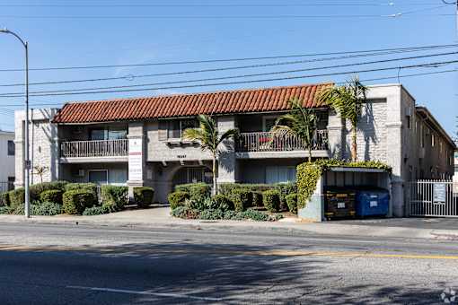 A building with a red tile roof and a blue dumpster in front.