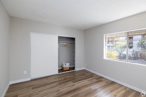 A room with a white door and a window with a view of a building outside.