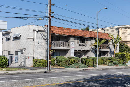 A building with a red tile roof is situated on a street corner.