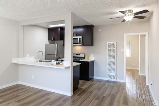 A kitchen with a white counter top and black cabinets.