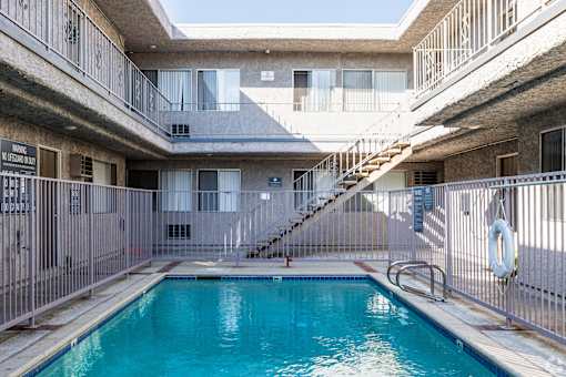 A pool in a courtyard surrounded by a metal fence.