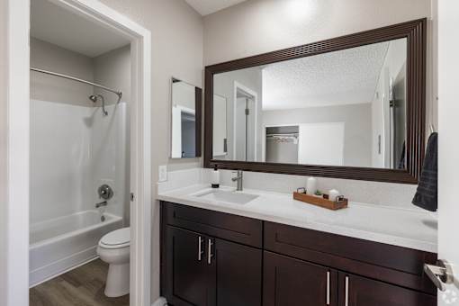 A bathroom with a white sink and a brown mirror.