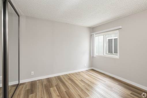 A room with a window and wooden flooring.