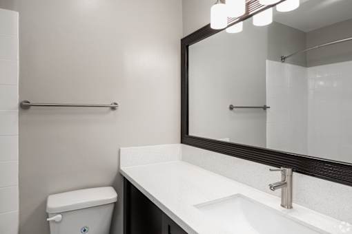 A white sink with a silver faucet and a mirror above it.