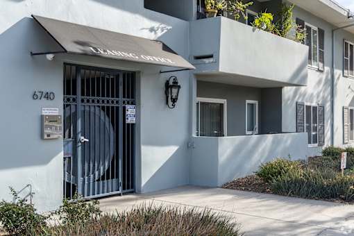 A white building with a black gate and a sign that reads "LEASING OFFICE".