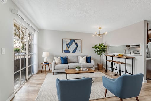 A living room with a couch, two chairs, and a dining table.