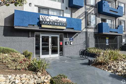 The image shows the front of the Windfaith Apartments building with a blue awning and glass doors.