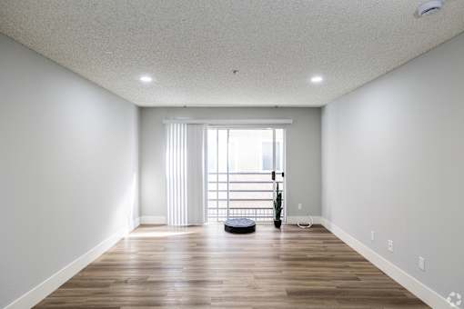 A room with wooden floors and a large window with blinds.