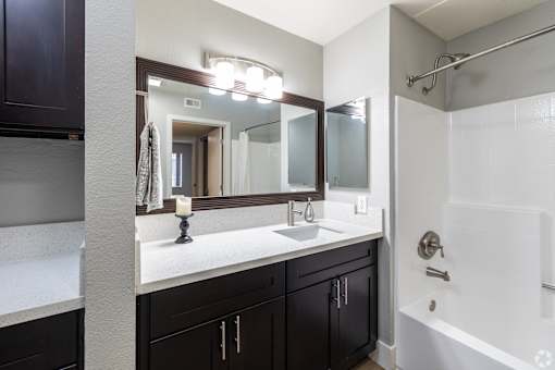 A bathroom with a white sink and a mirror above it.