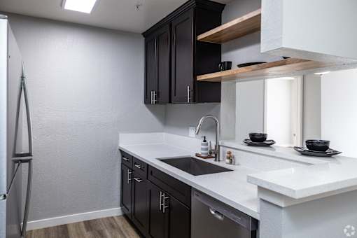 A modern kitchen with black cabinets and white countertops.