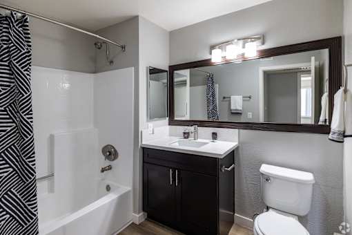 A bathroom with a black and white striped shower curtain.